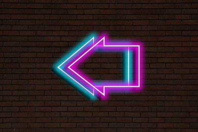 Image of Bright neon arrow-shaped pointer on brick wall