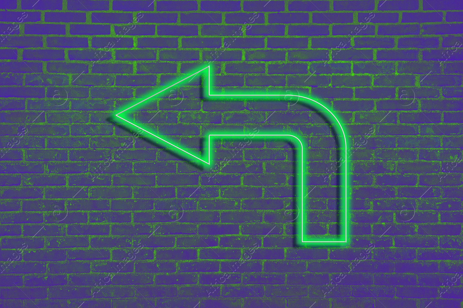 Image of Green neon arrow-shaped pointer on brick wall