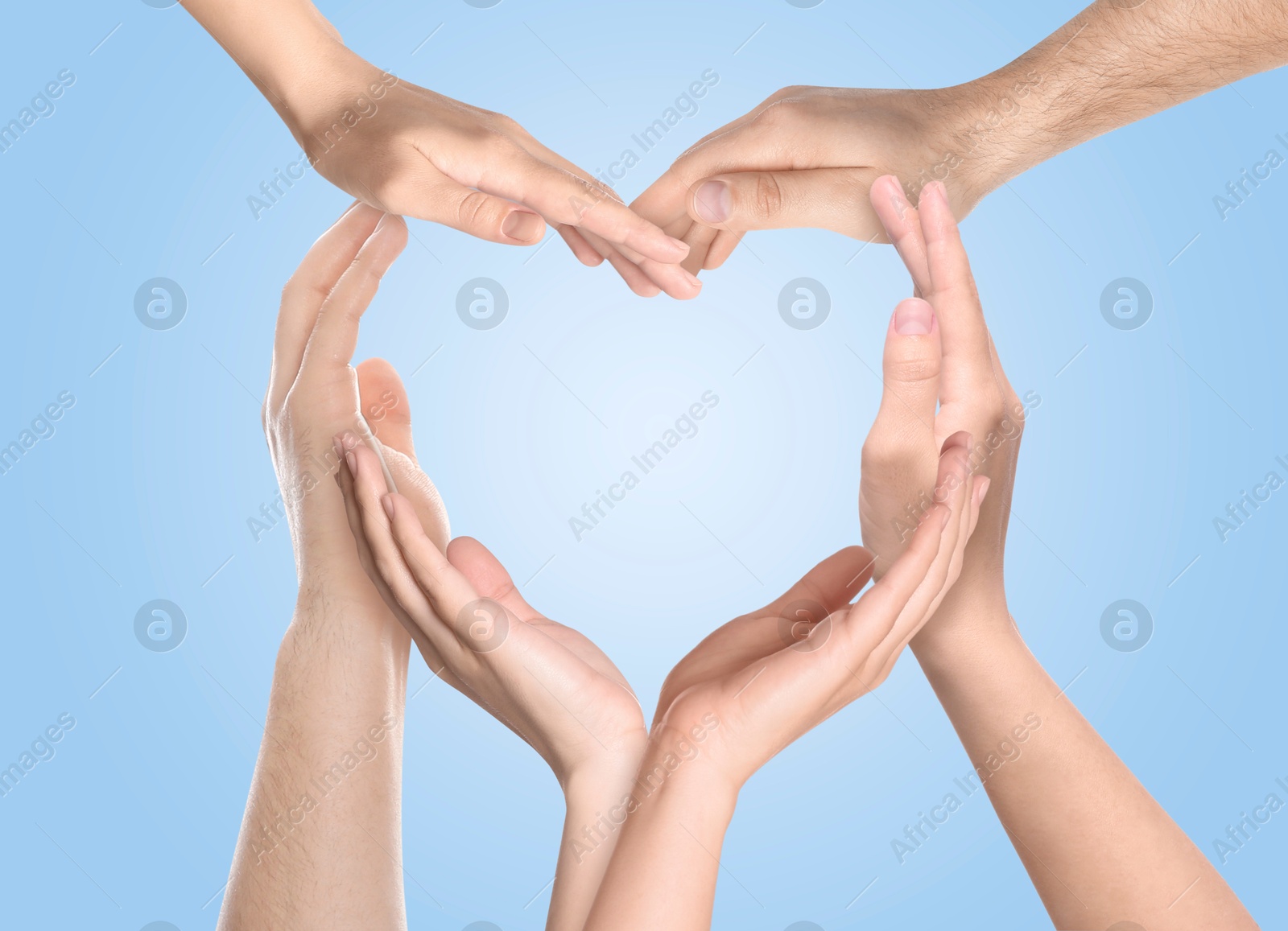 Image of Heart shape made with hands of different people on light blue background. Teamwork, unity, togetherness