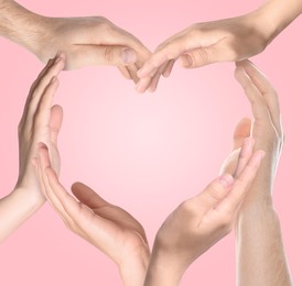 Image of Heart shape made with hands of different people on pink background. Teamwork, unity, togetherness