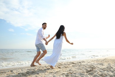 Photo of Lovely young couple running together on beach