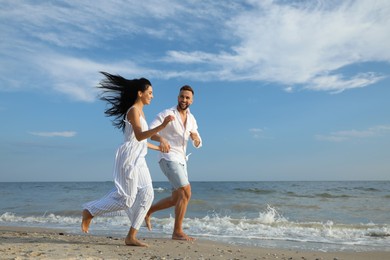 Happy young couple running together on beach