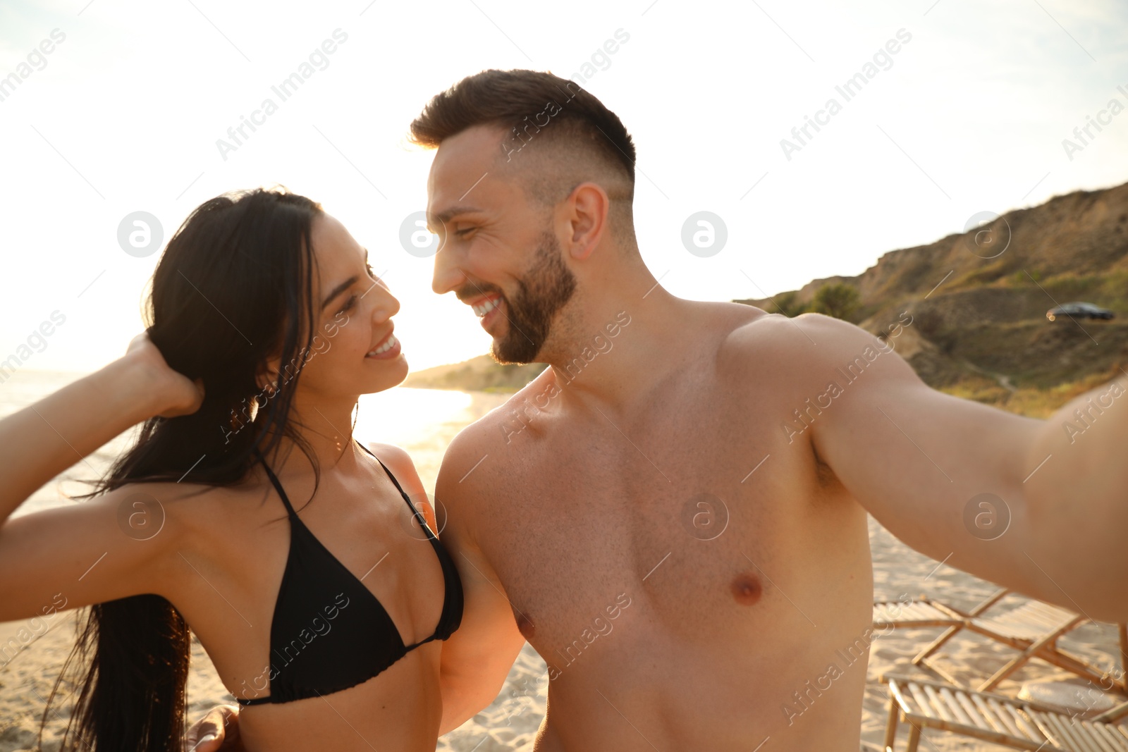 Photo of Happy young couple taking selfie on beach at sunset