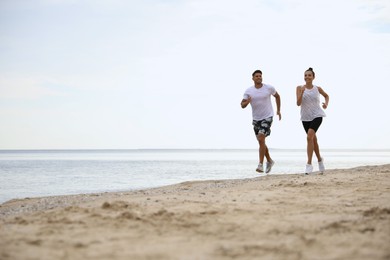 Photo of Couple running together on beach, space for text. Body training