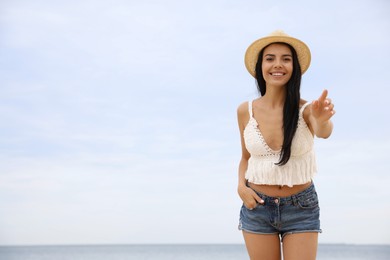 Photo of Beautiful young woman with beach hat near sea. Space for text