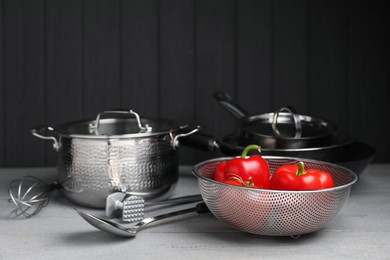 Photo of Dishware, cooking utensils and vegetables on grey wooden table