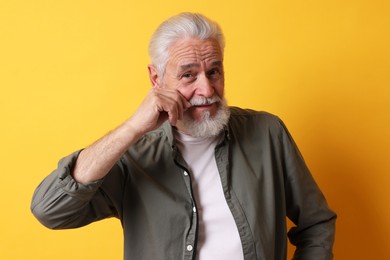 Photo of Portrait of senior man with gray beard on orange background