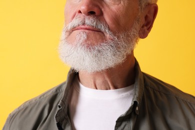 Photo of Senior man with gray beard on orange background, closeup