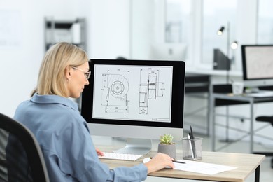 Photo of Technician making digital engineering drawing on computer at desk in office