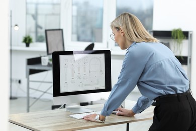 Photo of Technician making digital engineering drawing on computer at desk in office