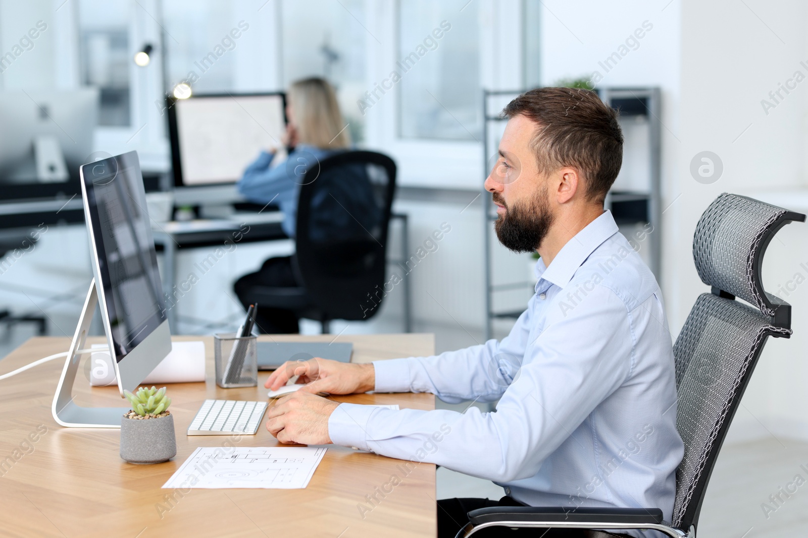 Photo of Technician making digital engineering drawing on computer at desk in office