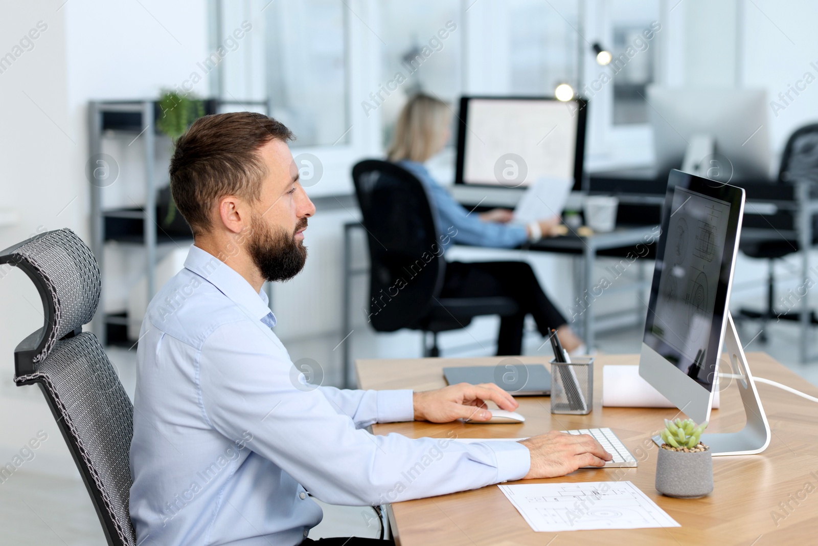 Photo of Technician making digital engineering drawing on computer at desk in office