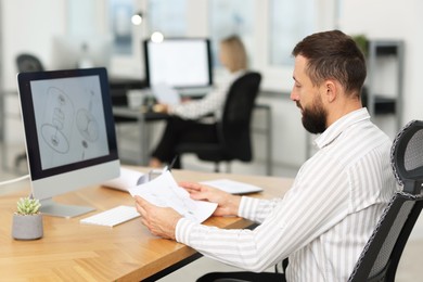 Photo of Technician making digital engineering drawing on computer at desk in office