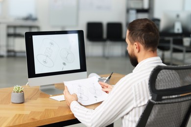 Photo of Technician making digital engineering drawing on computer at desk in office