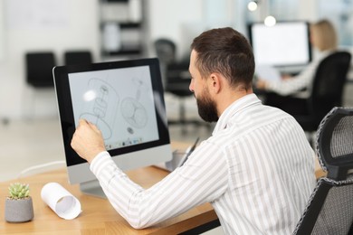 Photo of Technician making digital engineering drawing on computer at desk in office