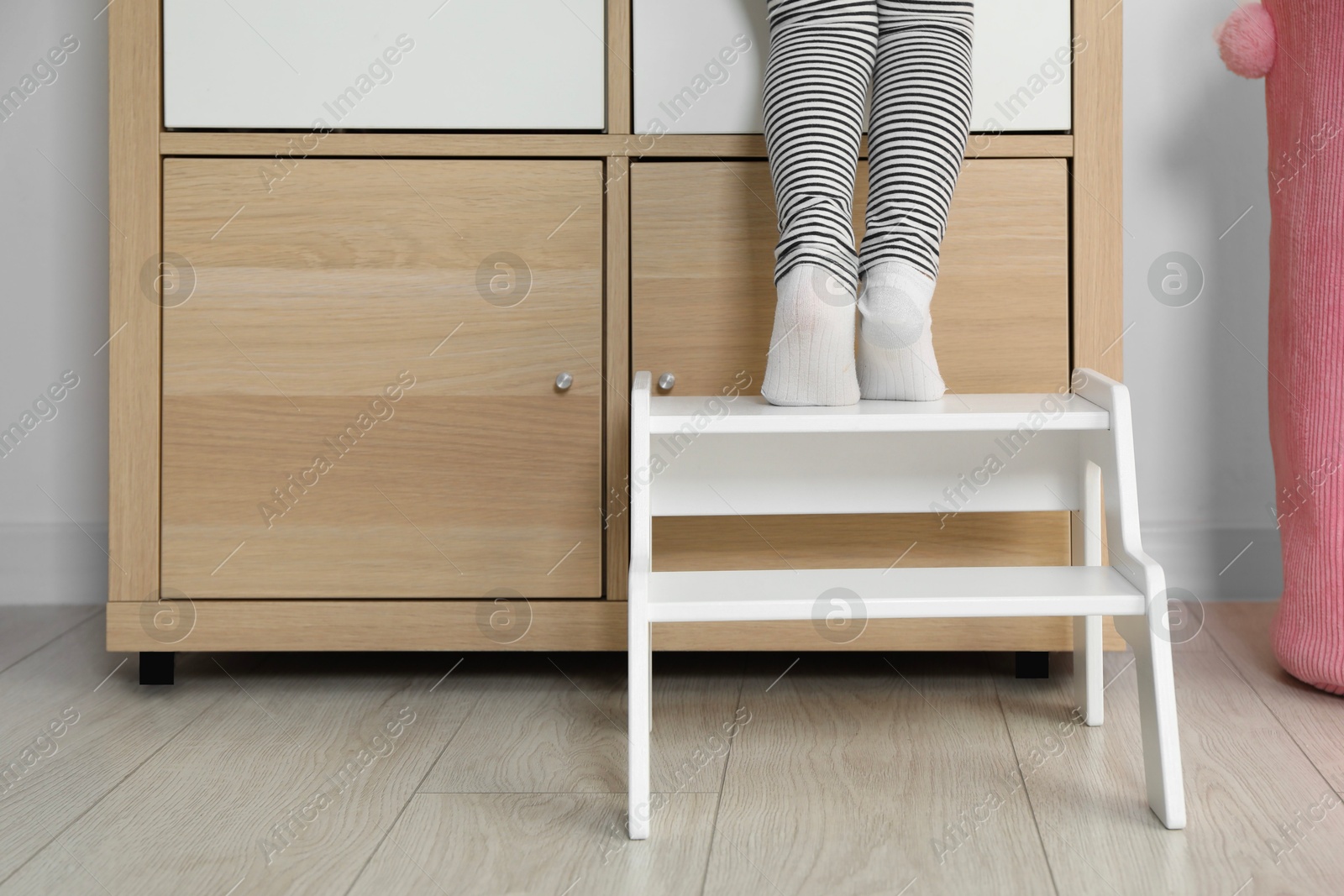 Photo of Little girl standing on step stool indoors, closeup