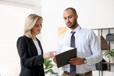 Photo of Coworkers with clipboard working together in office