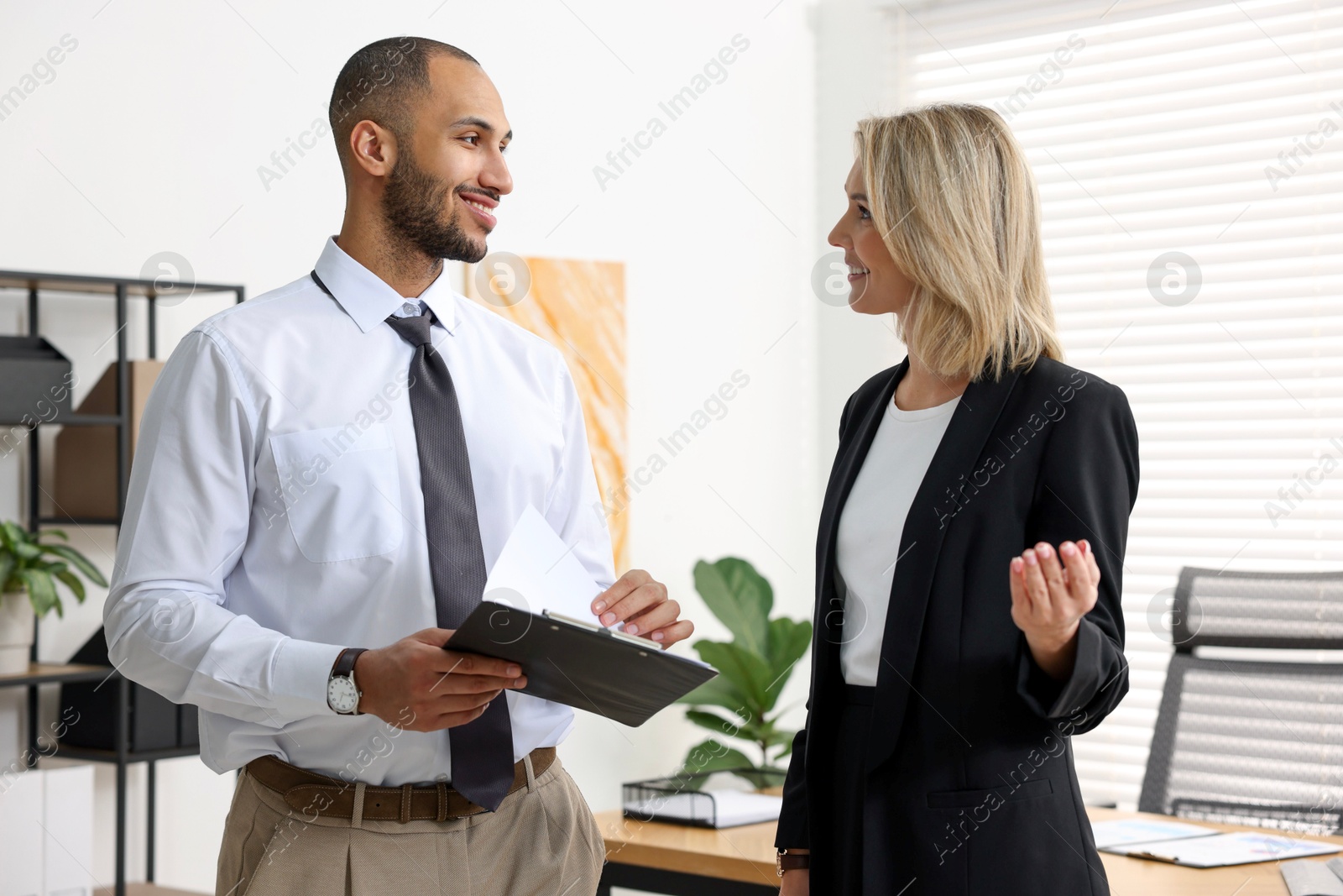 Photo of Coworkers with clipboard working together in office