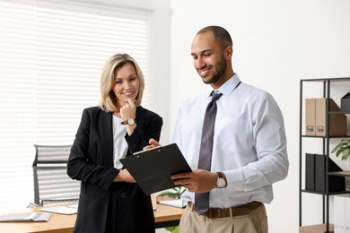 Photo of Coworkers with clipboard working together in office