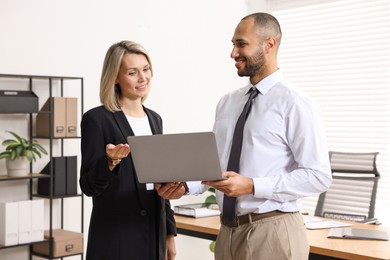 Photo of Coworkers with laptop working together in office