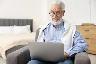 Photo of Bearded man with laptop in armchair at home