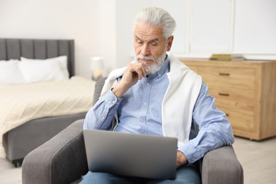 Photo of Bearded man with laptop in armchair at home