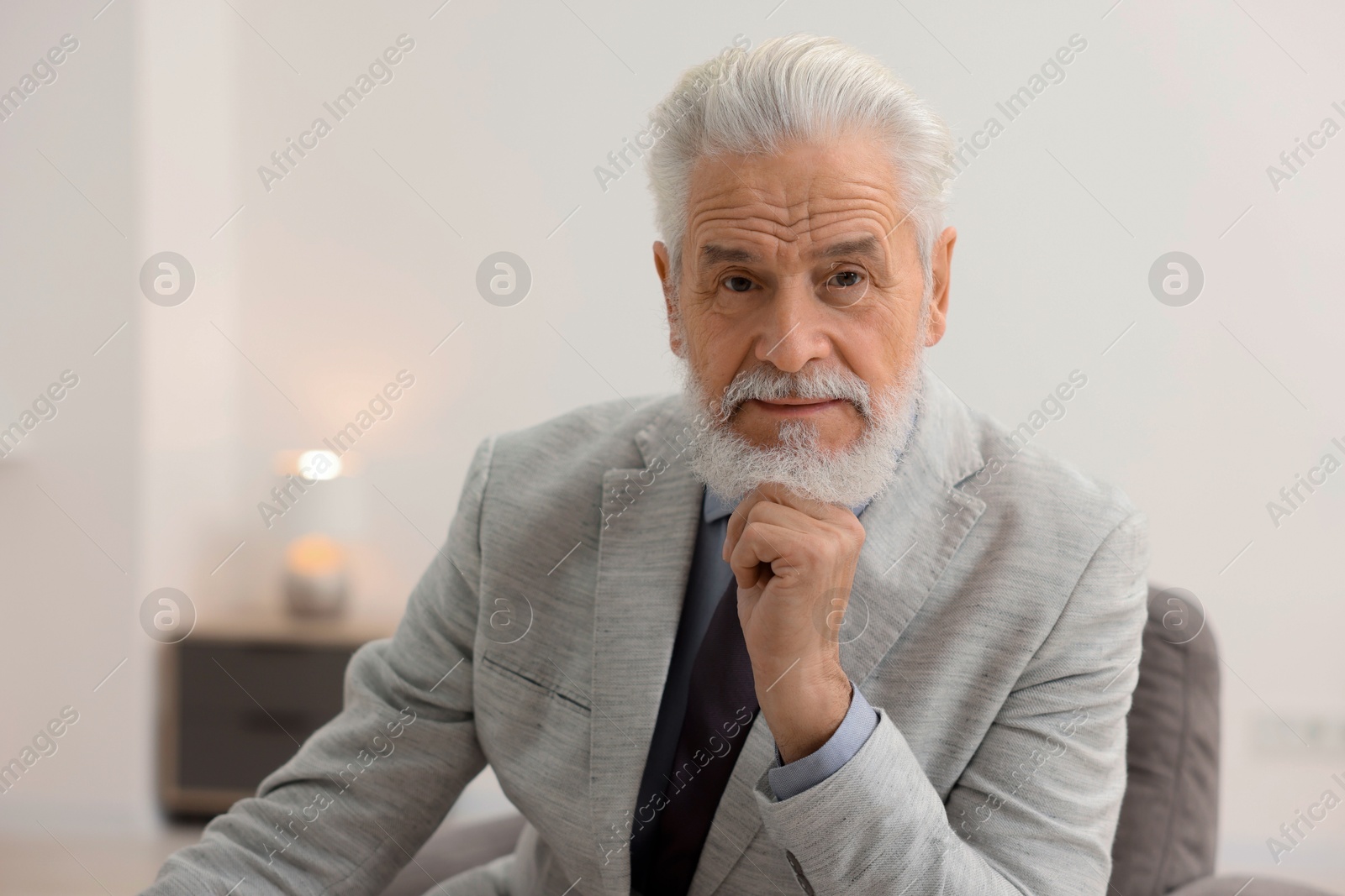 Photo of Portrait of handsome bearded man in armchair indoors