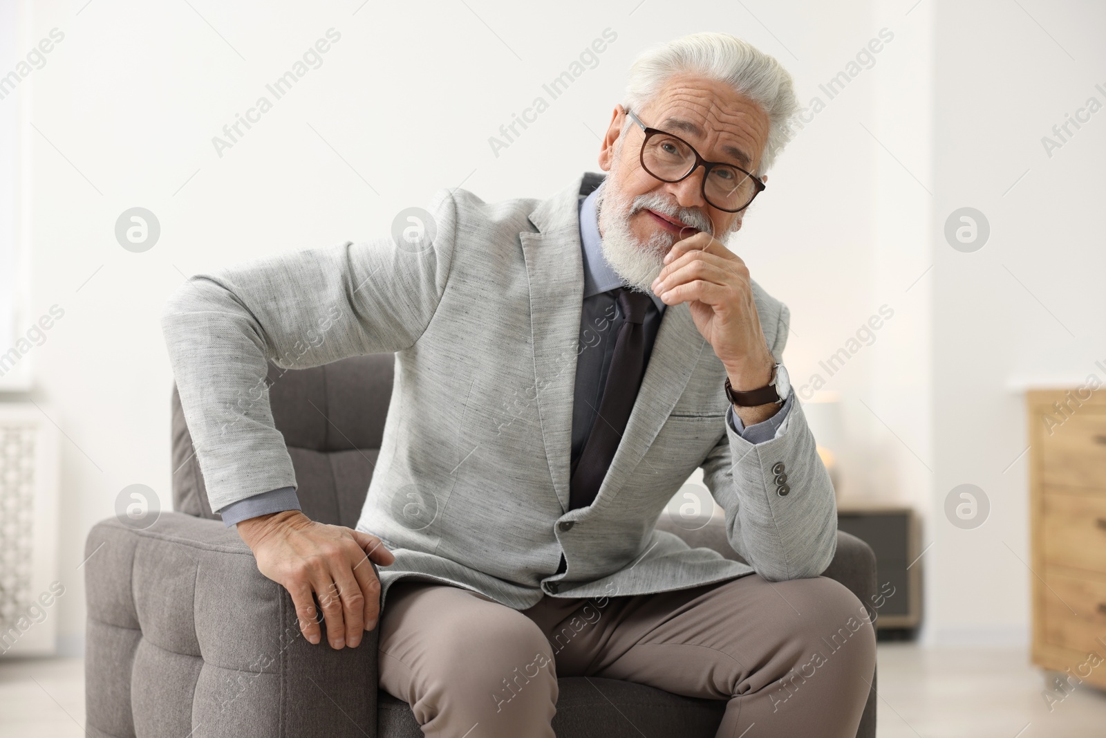 Photo of Portrait of handsome bearded man in armchair indoors