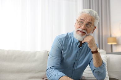 Photo of Portrait of handsome bearded man on sofa indoors, space for text