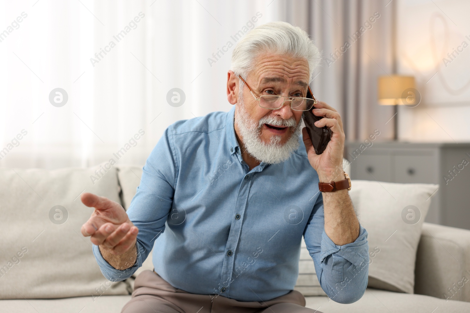 Photo of Handsome bearded man talking on smartphone indoors