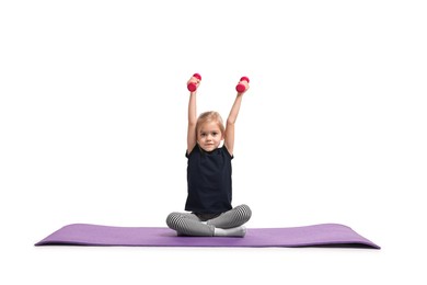 Photo of Little girl exercising with dumbbells on fitness mat against white background. Sport activity