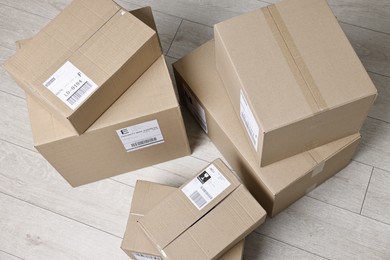 Photo of Cardboard parcel boxes with shipping labels on floor indoors, above view