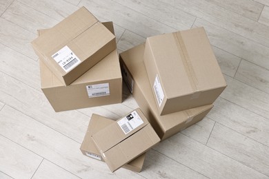 Photo of Cardboard parcel boxes with shipping labels on floor indoors, top view