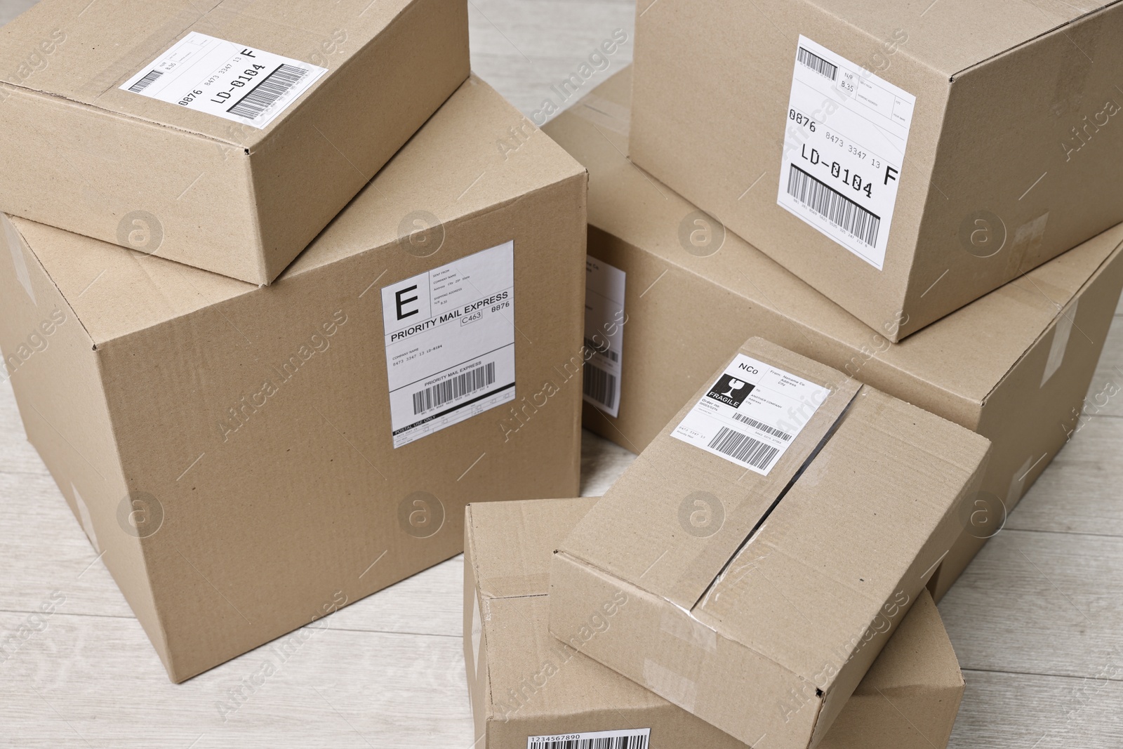 Photo of Cardboard parcel boxes with shipping labels on floor indoors, closeup