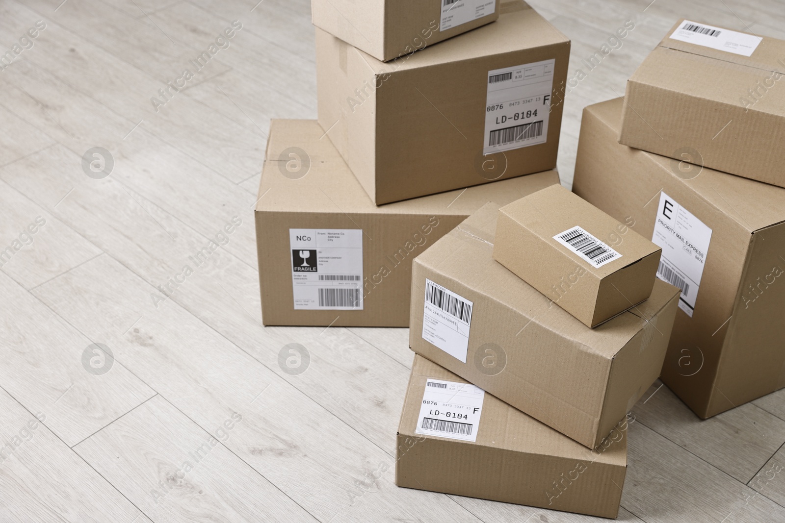 Photo of Cardboard parcel boxes with shipping labels on floor indoors, space for text