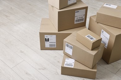 Cardboard parcel boxes with shipping labels on floor indoors, space for text