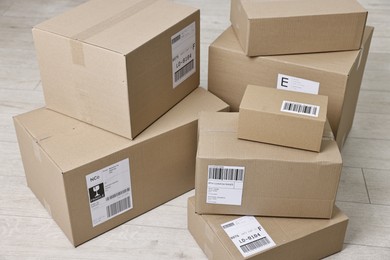 Photo of Cardboard parcel boxes with shipping labels on floor indoors, closeup