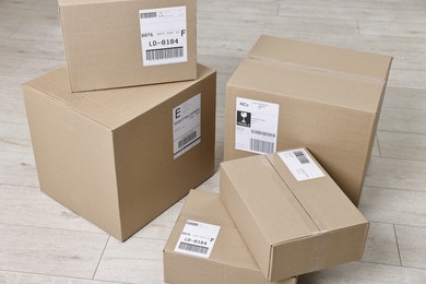 Photo of Cardboard parcel boxes with shipping labels on floor indoors