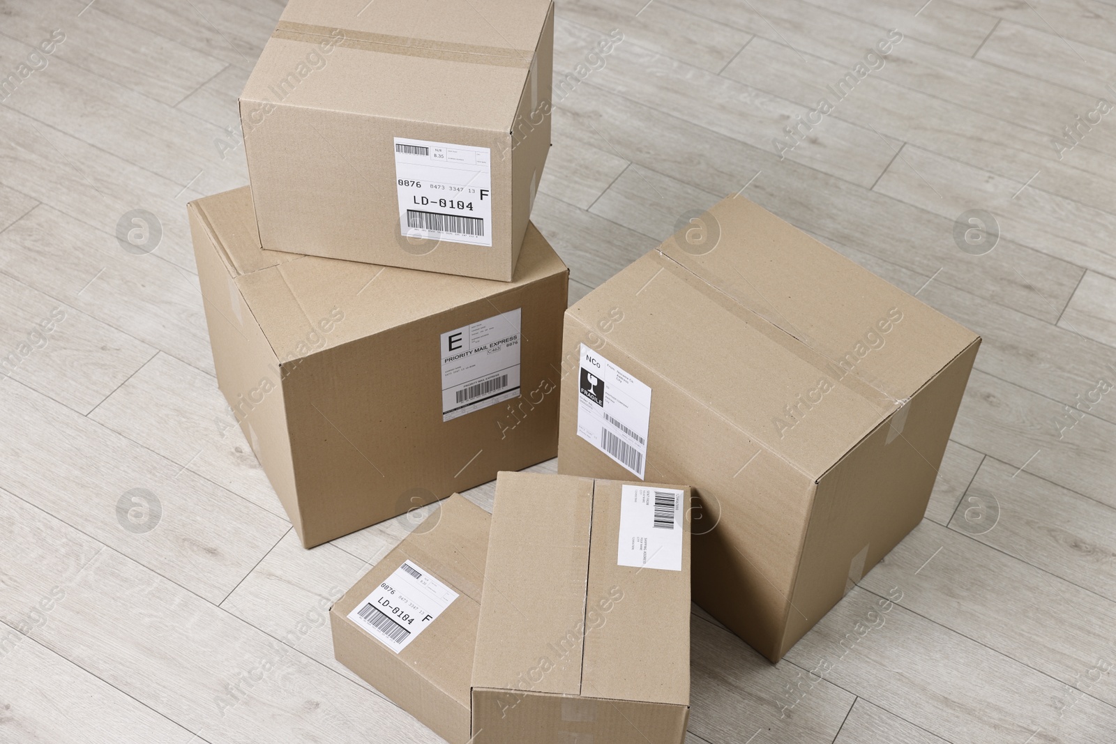 Photo of Cardboard parcel boxes with shipping labels on floor indoors