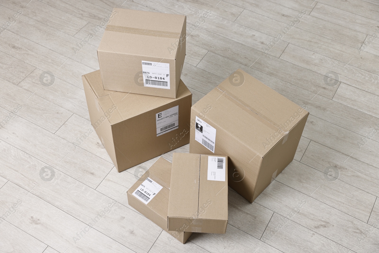 Photo of Cardboard parcel boxes with shipping labels on floor indoors