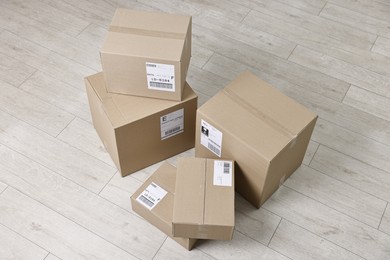 Photo of Cardboard parcel boxes with shipping labels on floor indoors