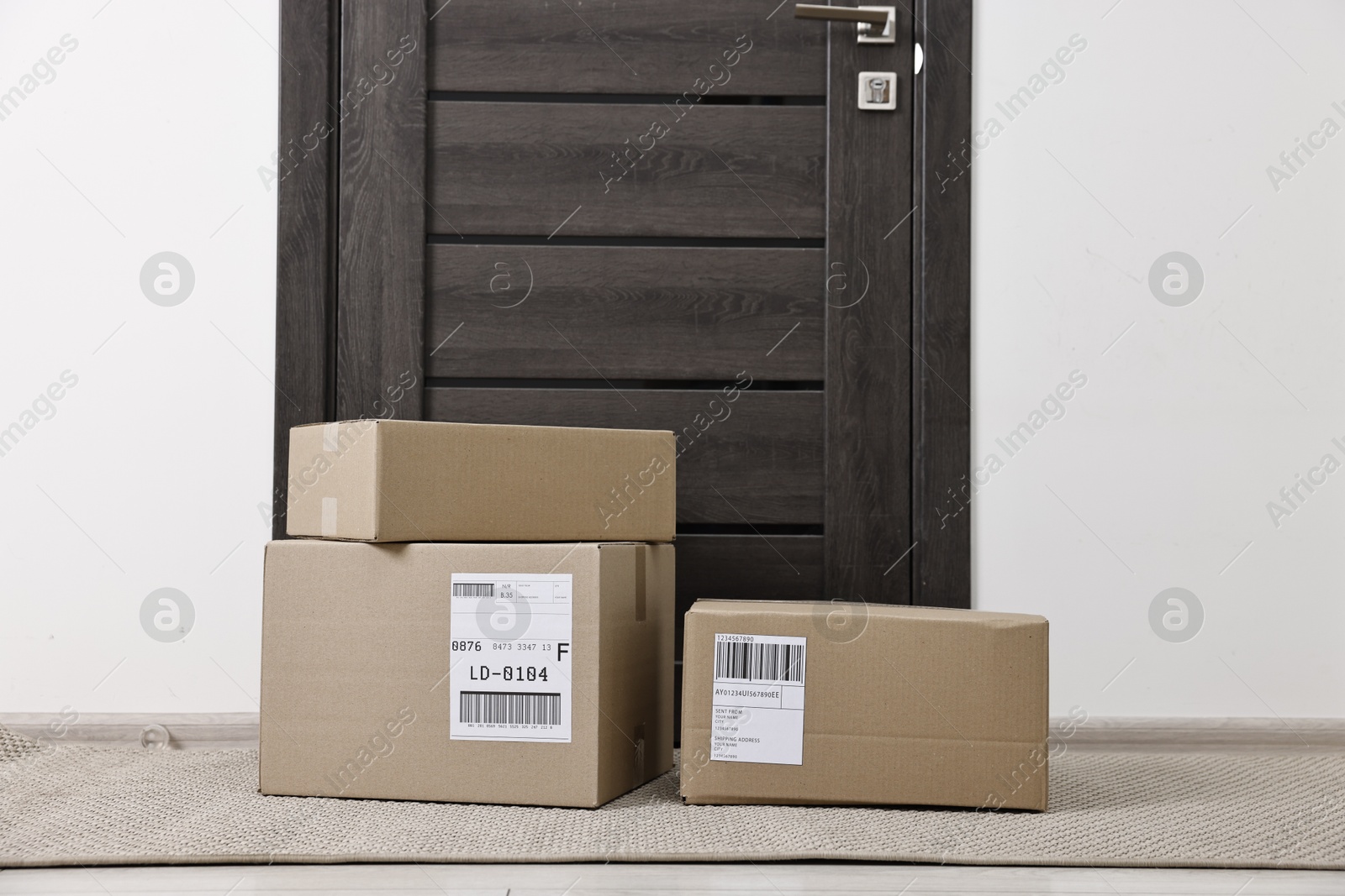 Photo of Cardboard parcel boxes with shipping labels near door indoors