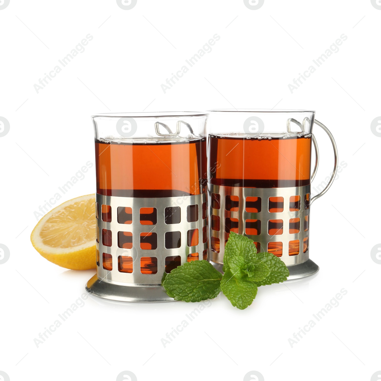 Photo of Glasses of aromatic tea in holders, lemon and mint isolated on white