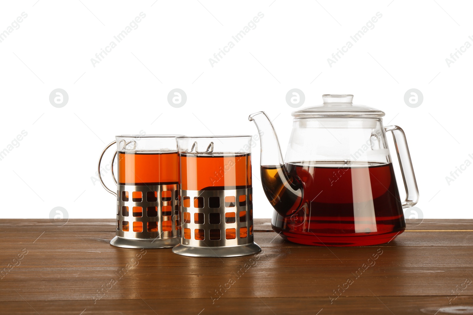 Photo of Glasses of aromatic tea in holders and teapot on wooden table against white background