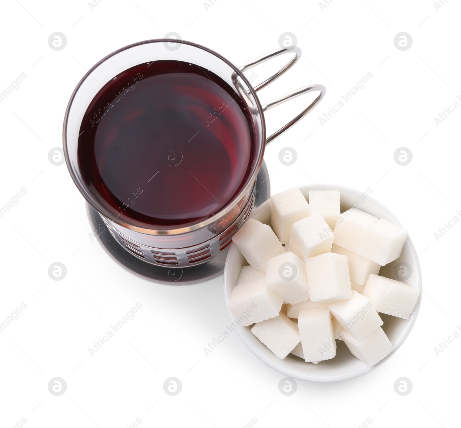 Photo of Glass of aromatic tea in holder and sugar cubes isolated on white, top view