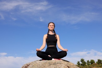 Photo of Young woman practicing outdoor yoga in mountains, space for text. Fitness lifestyle