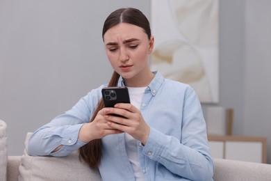 Photo of Depressed woman calling hotline for mental health help on sofa at home