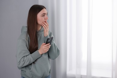 Photo of Desperate woman calling hotline for mental health help near window at home. Space for text