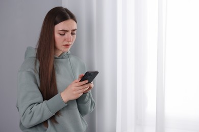 Photo of Desperate woman calling hotline for mental health help near window at home. Space for text