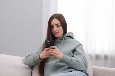 Photo of Depressed woman calling hotline for mental health help on sofa at home